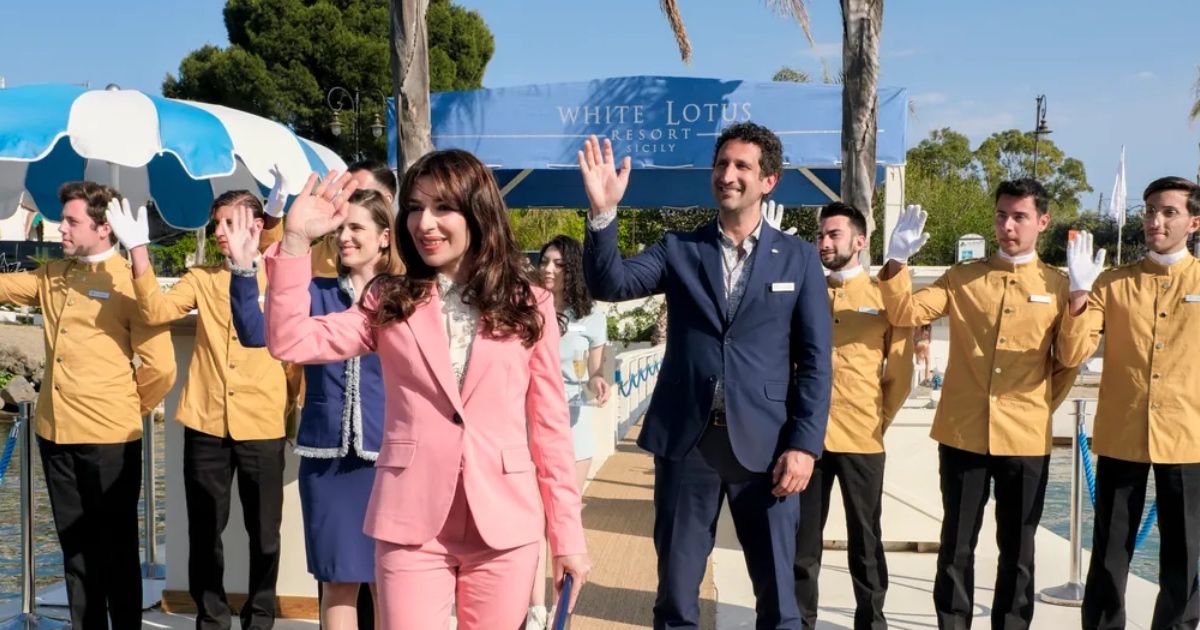 Group of people wave in front of luxury hotel.