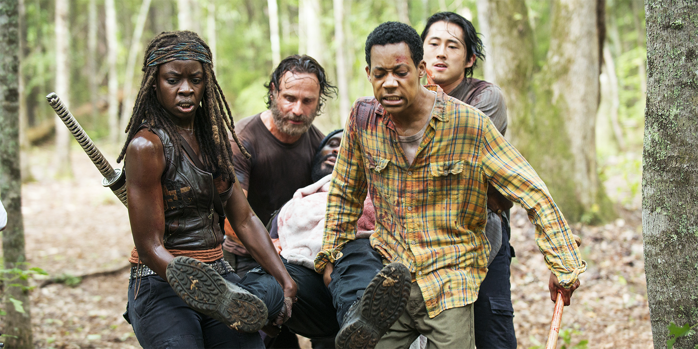 Four people carrying a wounded person in The Walking Dead
