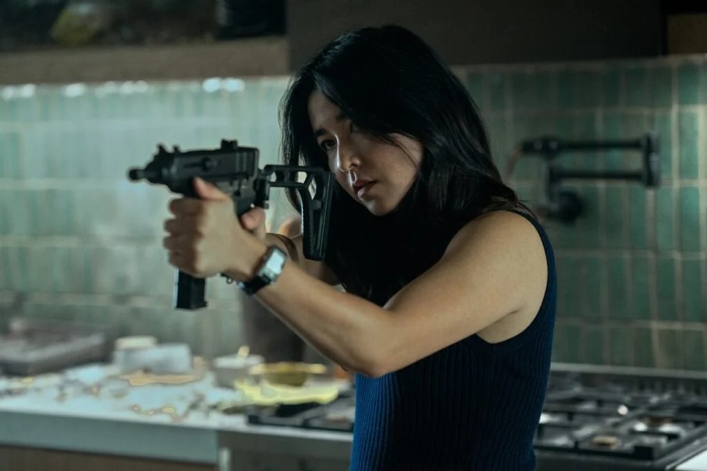 Maya Erksine vise une arme dans la série Mr. et Mrs.