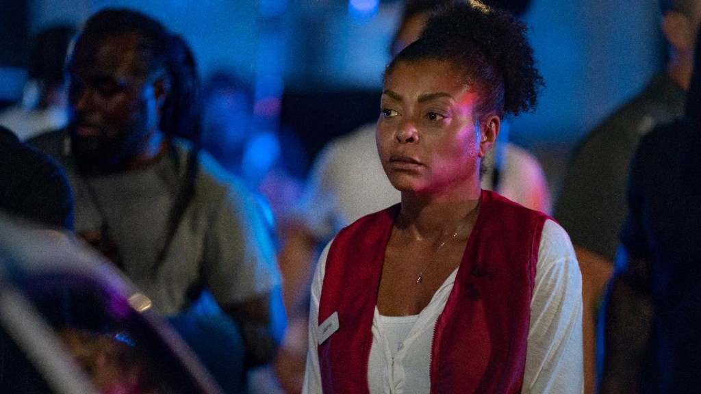 Taraji P. Henson se tient solennellement dans une scène nocturne tendue de la paille de Netflix, portant un gilet volontaire rouge sur une chemise blanche, entourée d'une foule floue sous des lumières d'urgence bleu et rouge dramatiques.