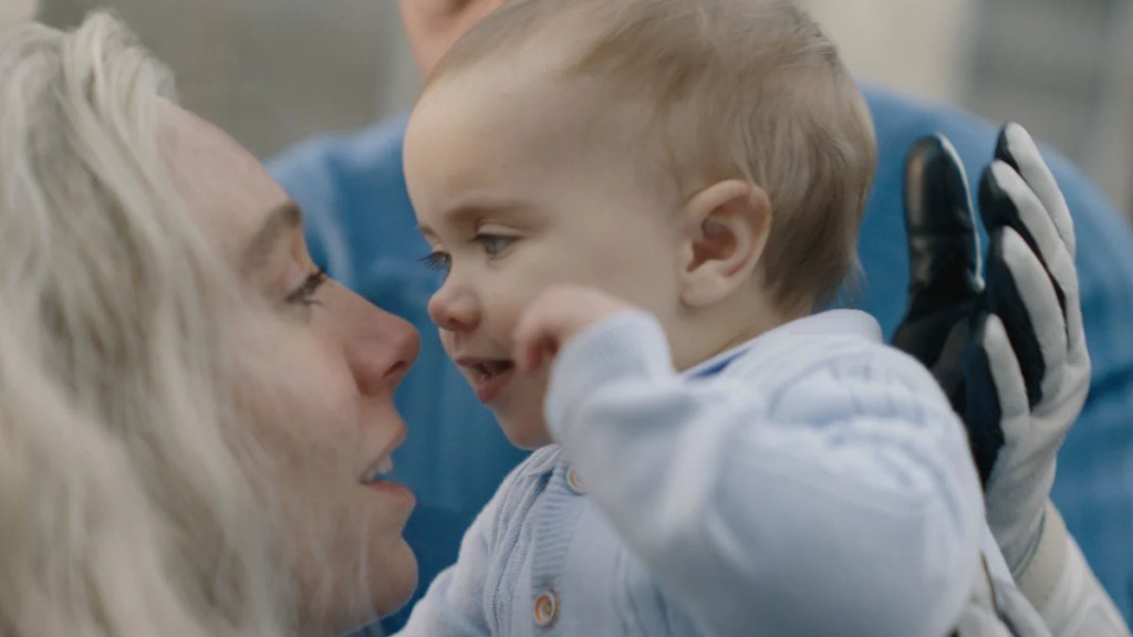 Sue Storm tient son bébé Franklin Reed près de son visage avec un sourire