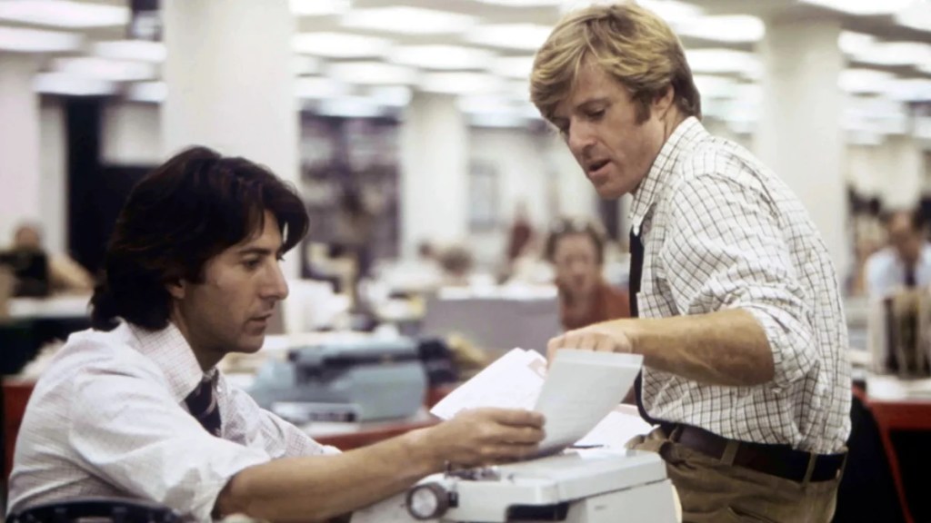 Dustin Hoffman (à gauche) et Robert Redford (à droite) sont assis à un bureau et consultent des papiers "Tous les hommes du président"